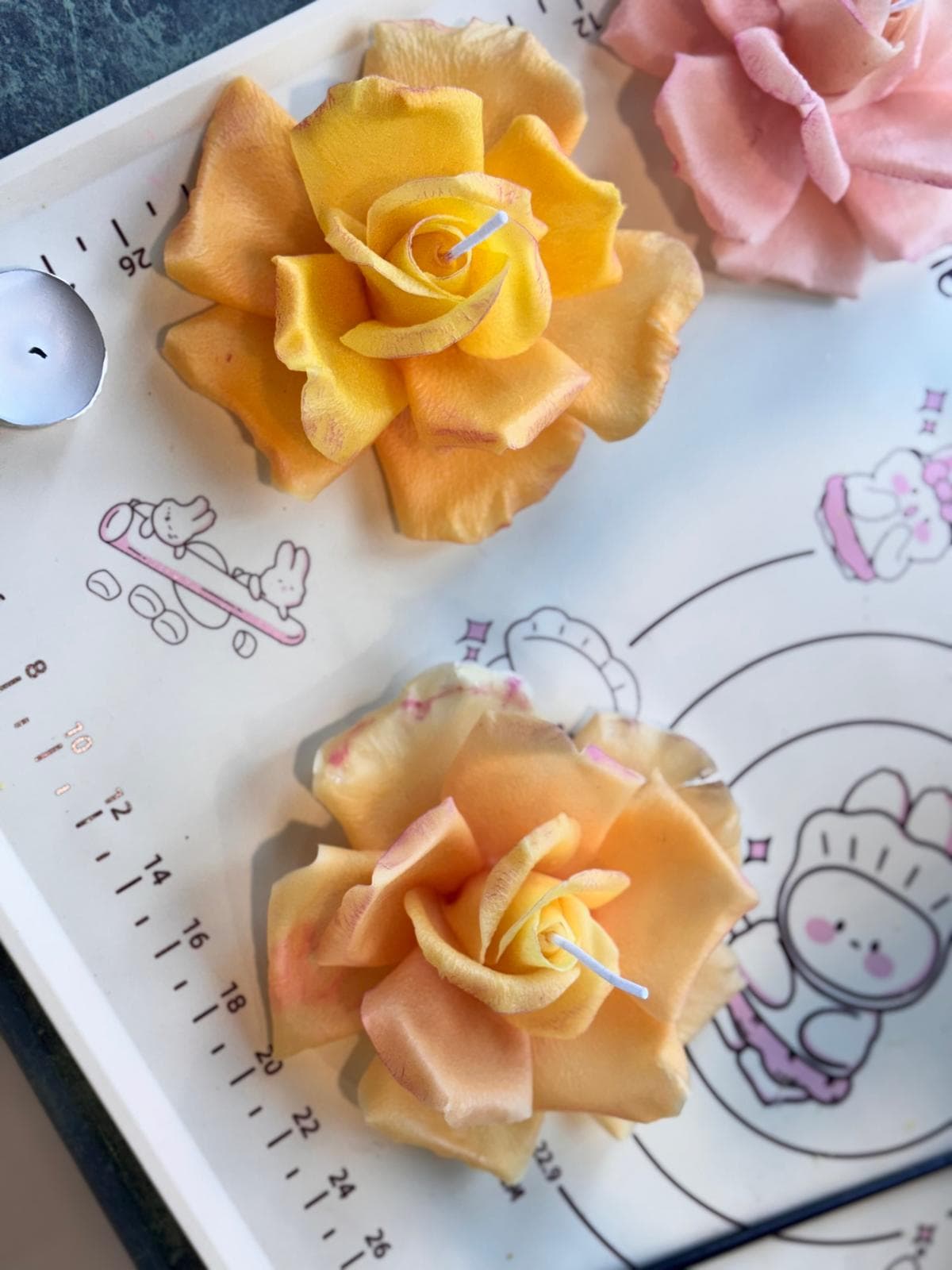 A handmade flower-shaped candle in soft pink wax.