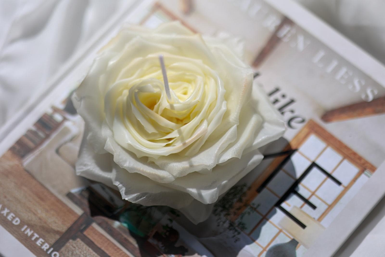 A cream rose-shaped candle on an open book.