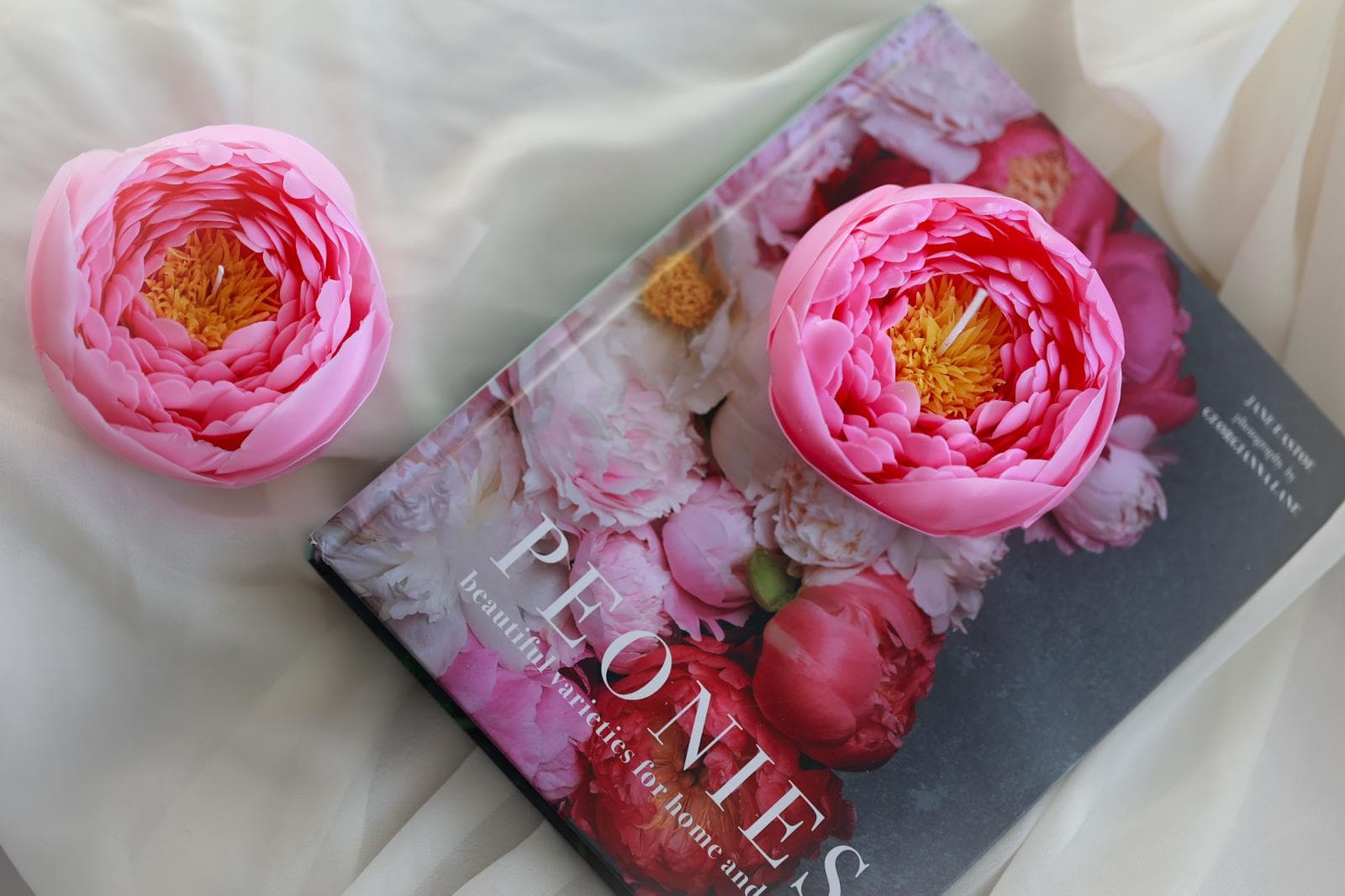 Pink floral candles resting on a flower-covered book.