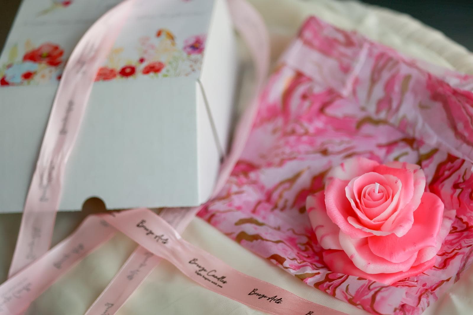 A pink rose candle arranged in floral packaging.