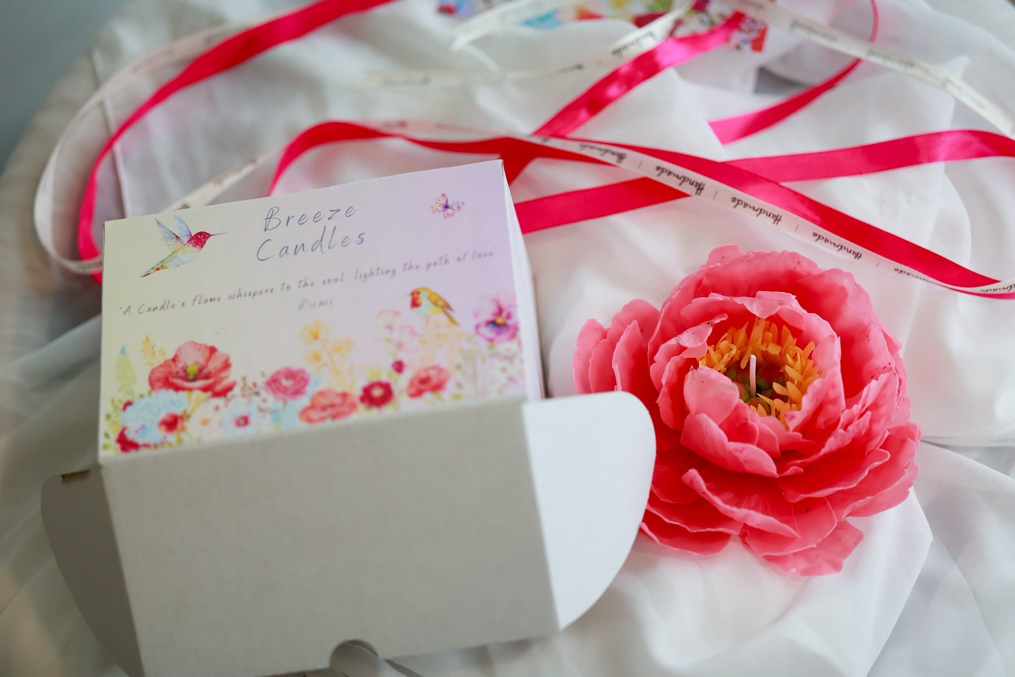 Pink flower candle and Breeze Candles packaging.